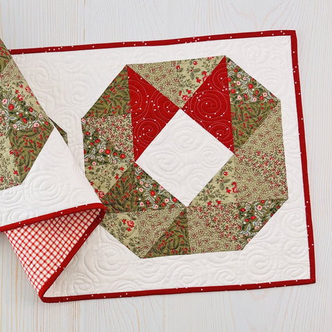 Wreath quilt block on a wooden background.