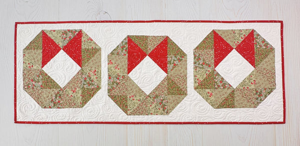 Quilted wreath table runner on a white background